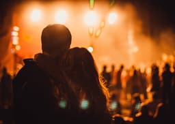 Couple devant un concert organisé par Hades Productions, lumières warm orange en arrière-plan